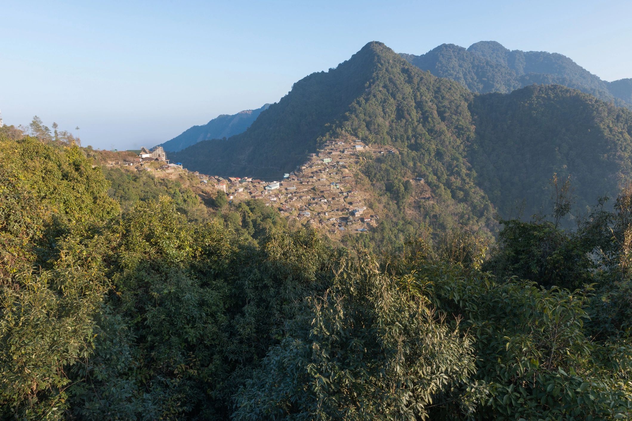 Distant mountain village surrounded by forest on a ridge