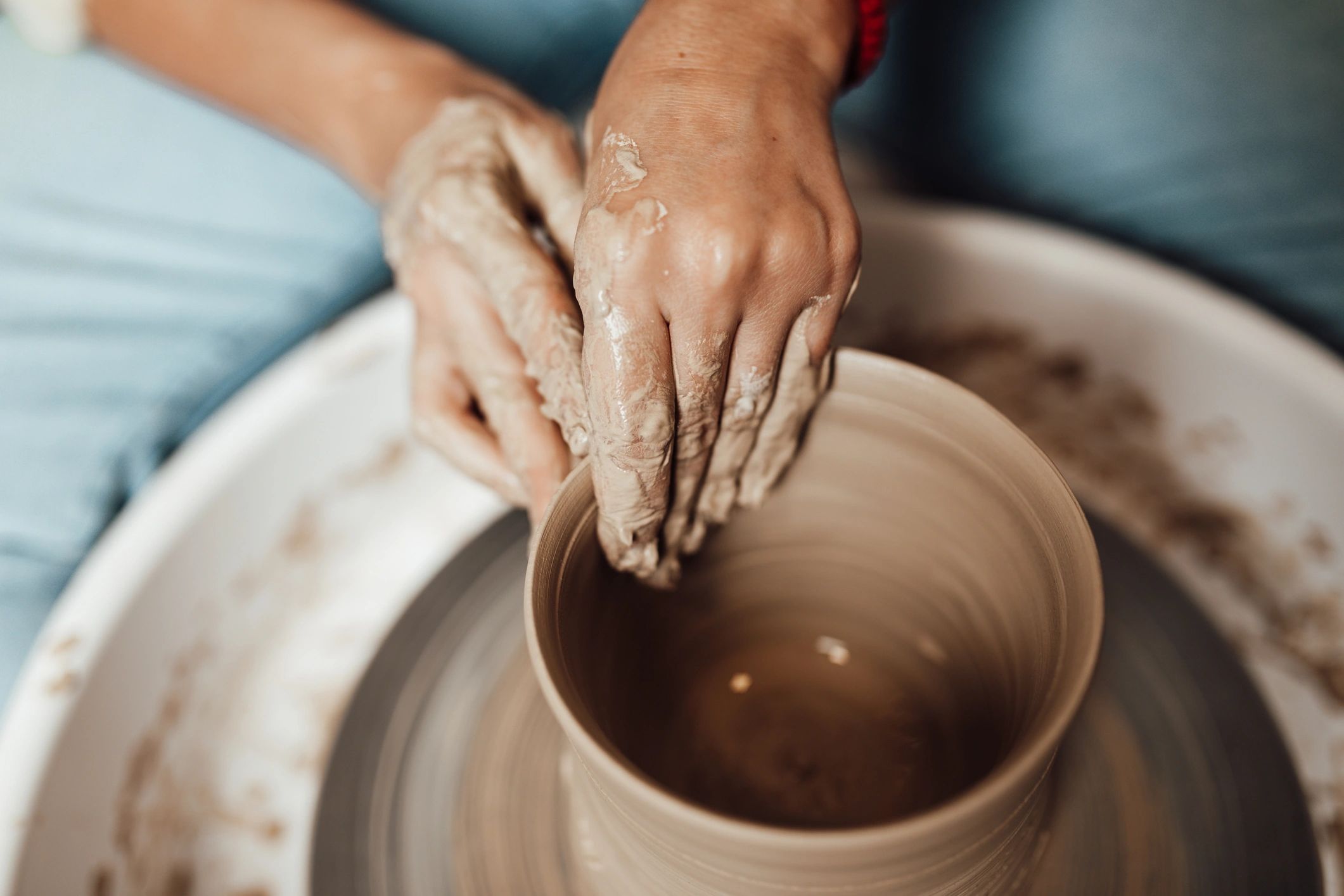 Potter’s hands shaping clay in a workshop