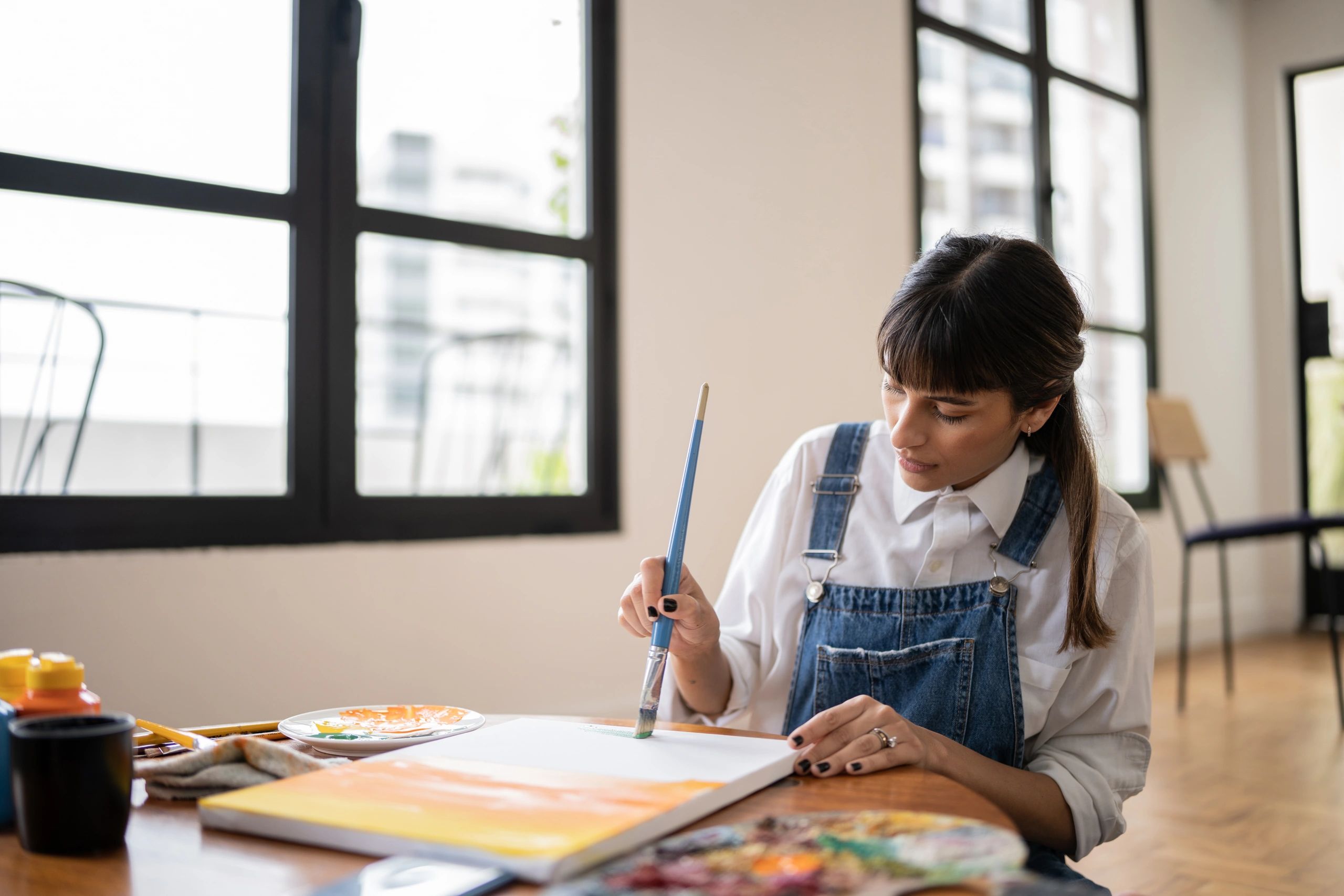 Young woman painting at home with calm focus