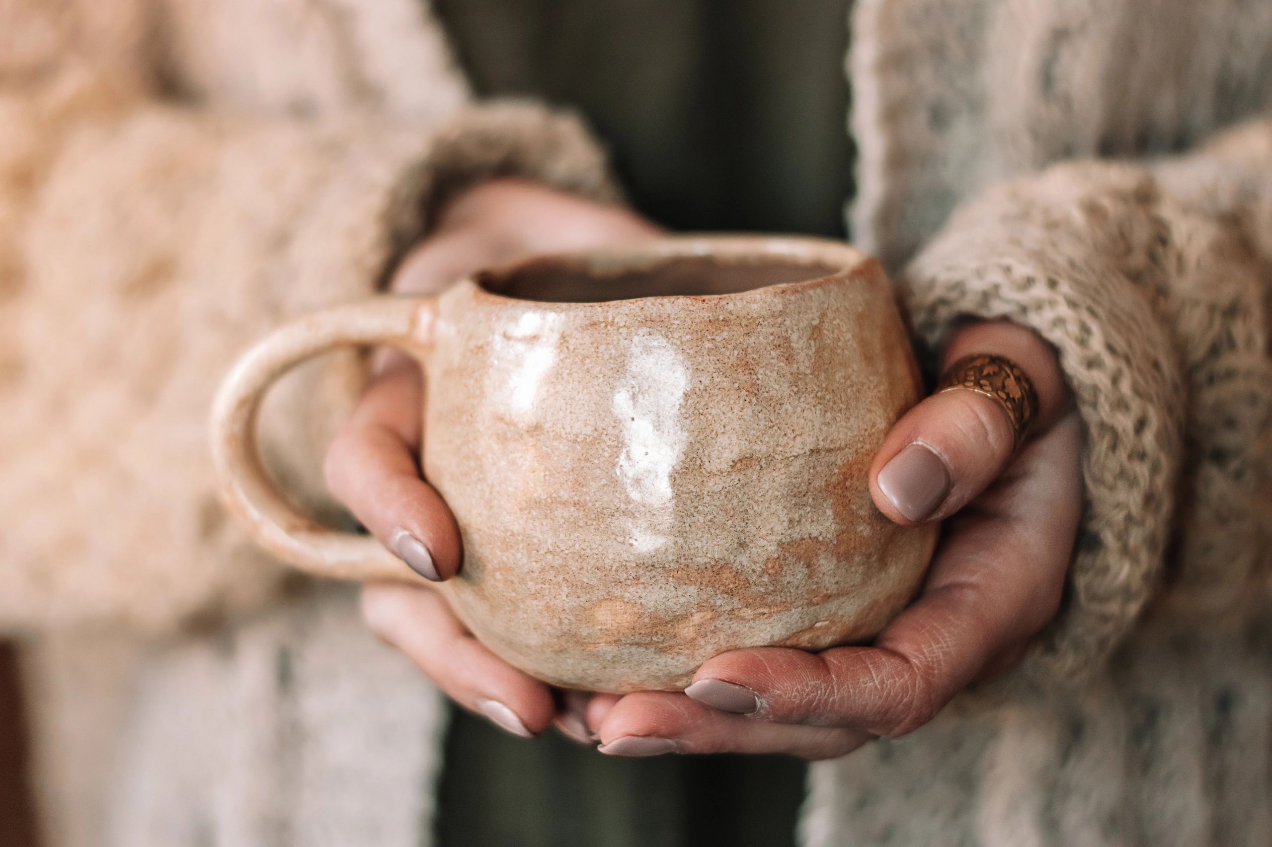 Close-up of hands holding a handmade clay mug