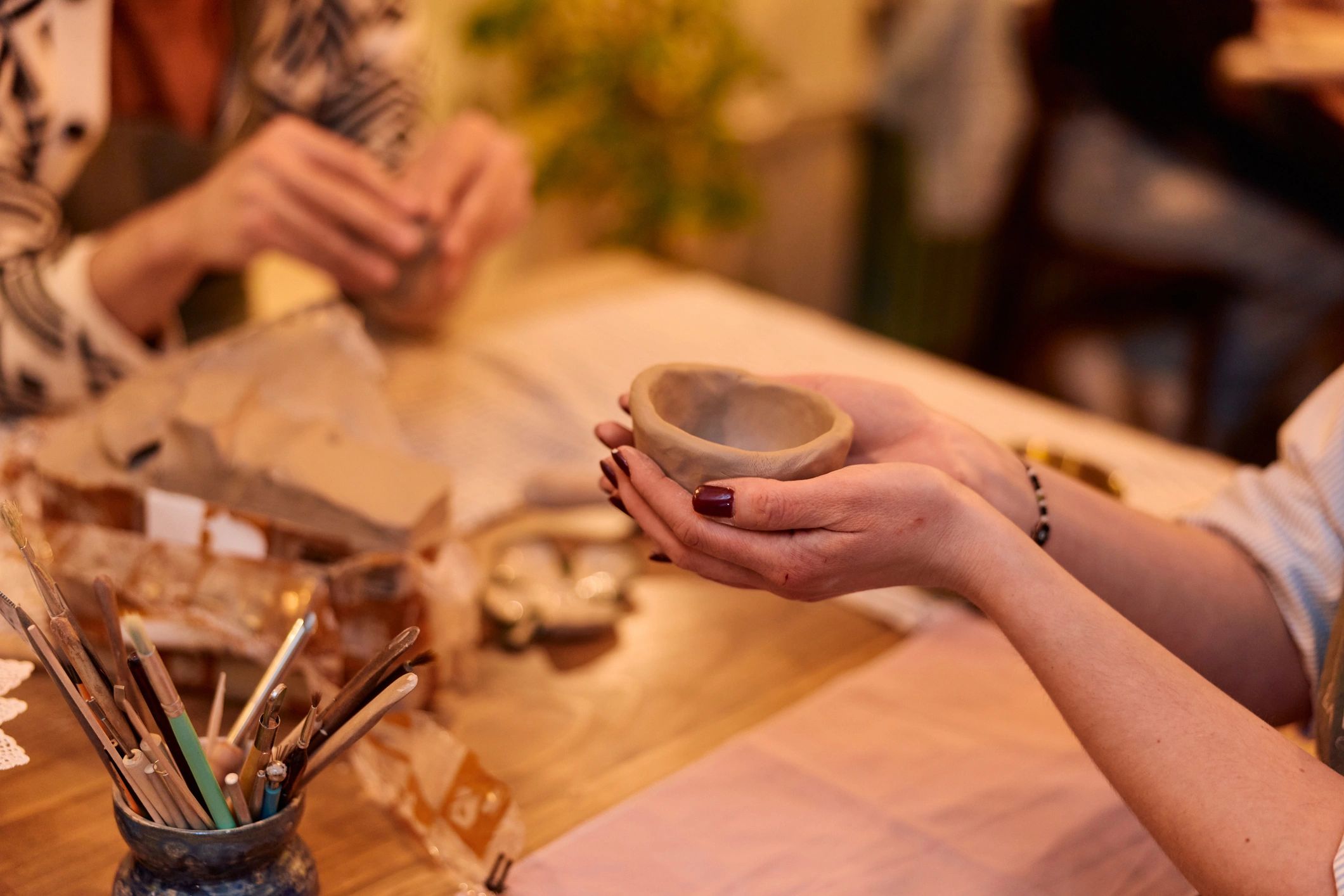 Hands holding a handmade clay bowl during a pottery workshop